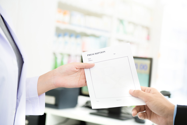 Customer (patient) giving prescription to pharmacist